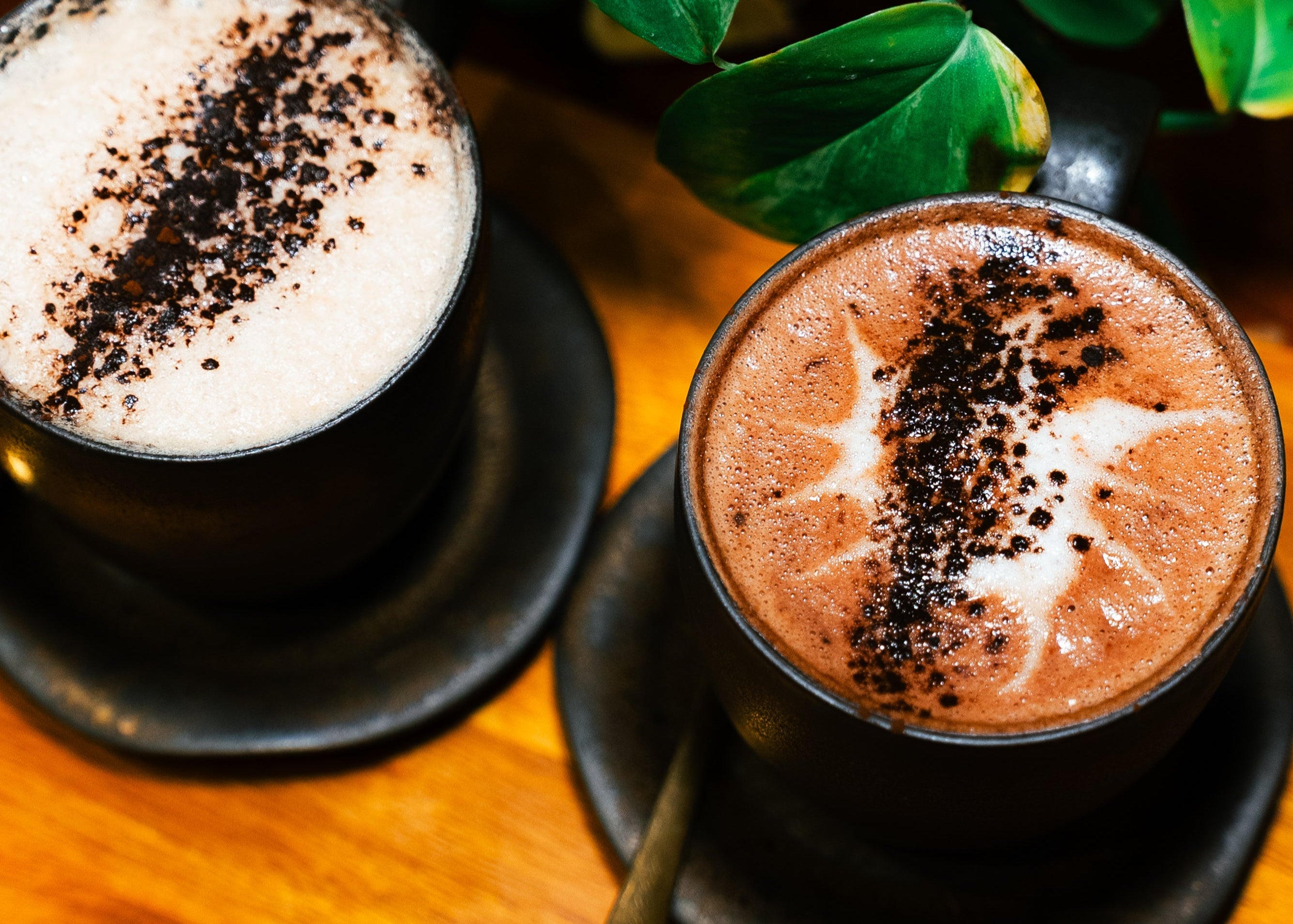Two cups of hot chocolate with whipped cream and chocolate shavings on a wooden board with 'Chocolate and Love' text.
